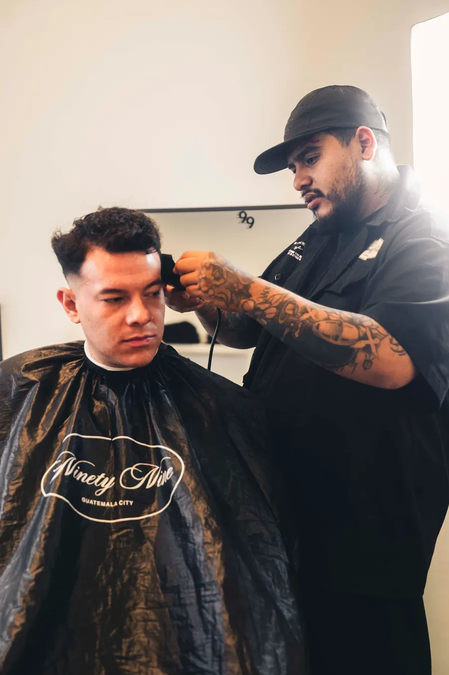 Barbero de Studio 99 realizando un corte con capa Ninety Nine